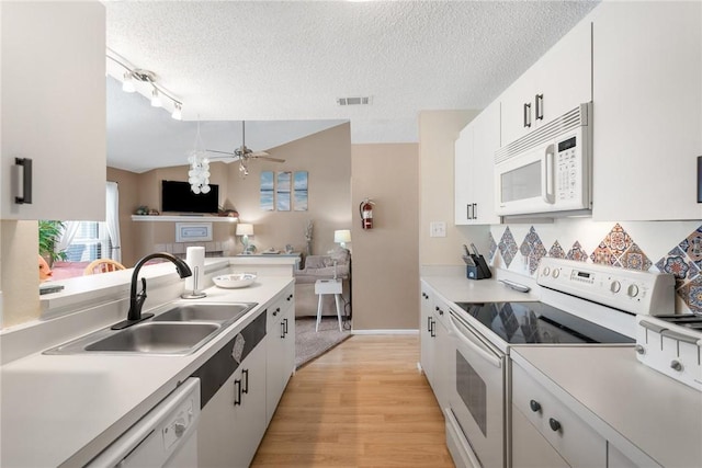 kitchen with sink, a textured ceiling, white cabinets, and white appliances