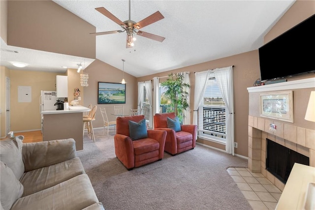 living room featuring light colored carpet, vaulted ceiling, a tile fireplace, and ceiling fan