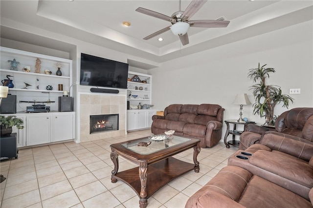 living room with light tile patterned floors, built in shelves, and a tray ceiling