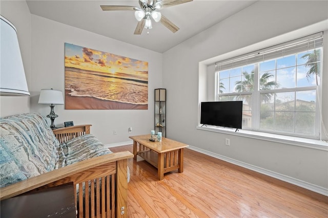 living room with a ceiling fan, baseboards, and wood finished floors