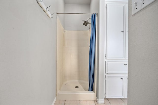 full bath with tile patterned flooring, a shower stall, and baseboards