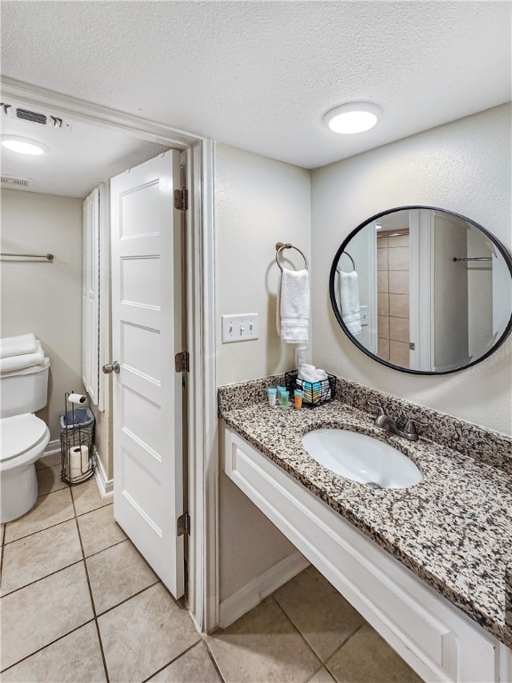 bathroom featuring vanity, tile patterned floors, toilet, and a textured ceiling