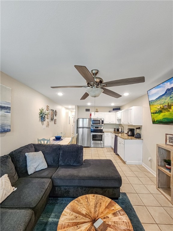 living room featuring light tile patterned floors, ceiling fan, and sink