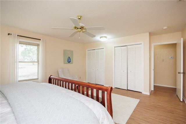 bedroom with multiple closets, ceiling fan, and light hardwood / wood-style flooring