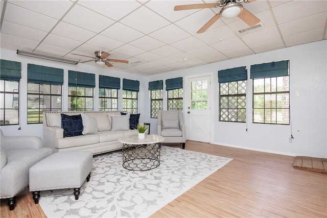 living room with hardwood / wood-style floors, a drop ceiling, and ceiling fan