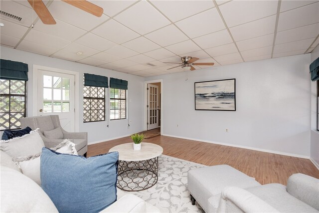 living room featuring hardwood / wood-style floors, a drop ceiling, and ceiling fan