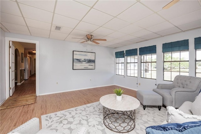 sitting room featuring ceiling fan, wood-type flooring, and a drop ceiling