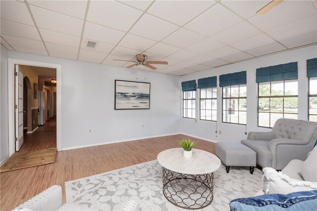 sitting room with hardwood / wood-style flooring, ceiling fan, and a drop ceiling