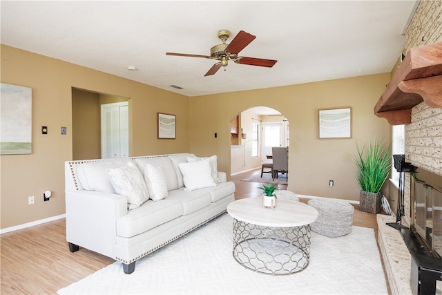 living room featuring ceiling fan, a fireplace, and light hardwood / wood-style floors