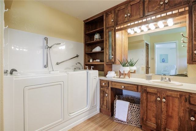 bathroom with vanity, washer / clothes dryer, hardwood / wood-style flooring, and a tub