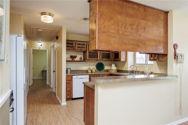 kitchen featuring sink, white appliances, kitchen peninsula, and light wood-type flooring