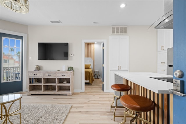 interior space featuring a breakfast bar, stainless steel fridge, white cabinetry, and light hardwood / wood-style flooring