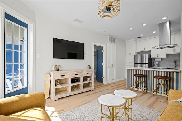 living room featuring sink and light hardwood / wood-style flooring