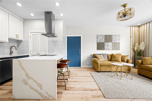 kitchen featuring white cabinetry, dishwasher, wall chimney exhaust hood, backsplash, and light wood-type flooring