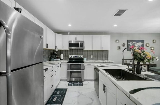 kitchen featuring stainless steel appliances, backsplash, white cabinets, and sink