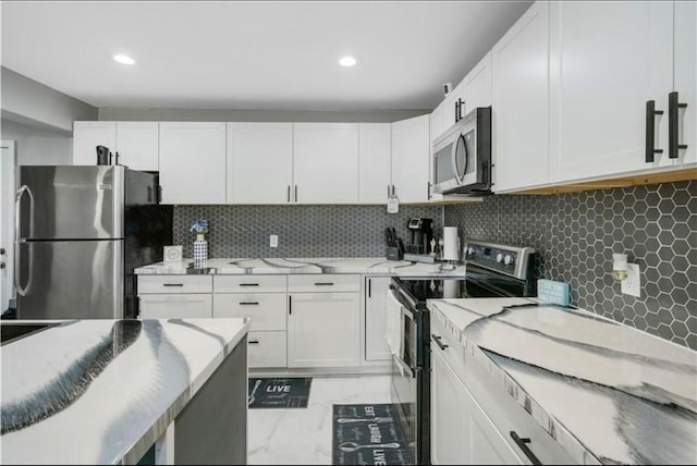 kitchen featuring light stone counters, stainless steel appliances, white cabinetry, and tasteful backsplash