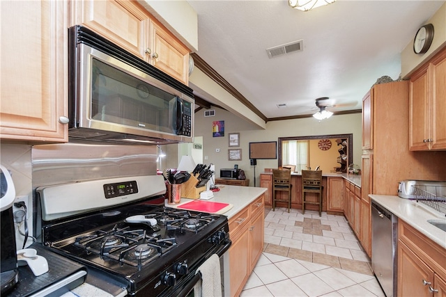 kitchen with stainless steel appliances, ceiling fan, light tile patterned floors, and ornamental molding