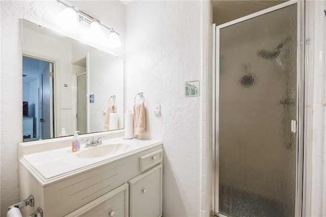 bathroom with a shower with shower door and vanity