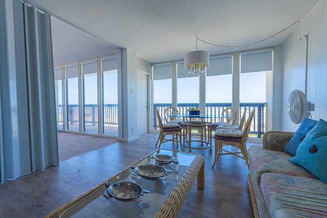 living room featuring a wall of windows, a water view, an inviting chandelier, and dark hardwood / wood-style flooring