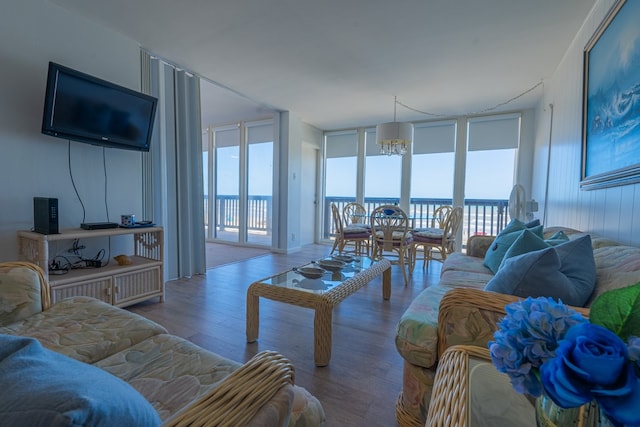 living room featuring hardwood / wood-style floors, an inviting chandelier, a water view, and floor to ceiling windows