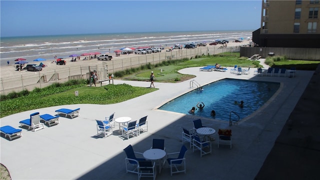 view of pool with a beach view, a water view, and a patio