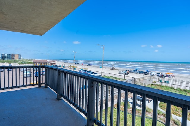 balcony with a water view and a view of the beach