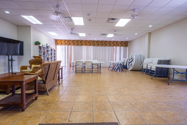 interior space with a paneled ceiling and ceiling fan