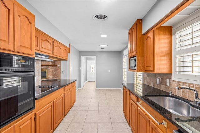 kitchen with plenty of natural light, light tile patterned floors, black appliances, under cabinet range hood, and a sink