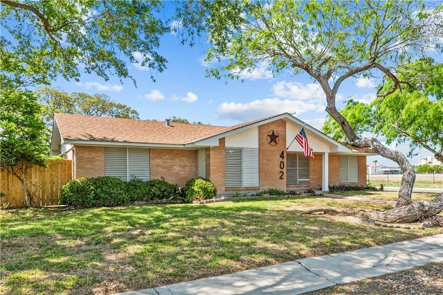 view of front of house featuring brick siding, fence, and a front lawn