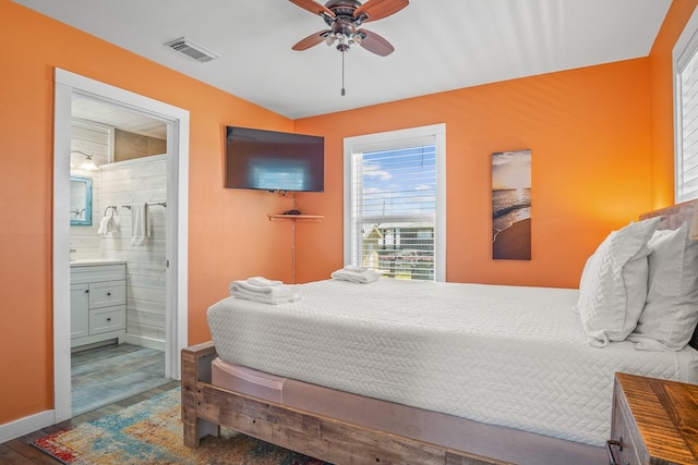 bedroom featuring vaulted ceiling, hardwood / wood-style flooring, ceiling fan, and ensuite bath