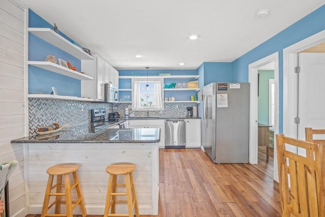 1030 Tenth St S, Port Aransas, TX 78373 - kitchen featuring open shelves, appliances with stainless steel finishes, a peninsula, dark stone countertops, and white cabinets