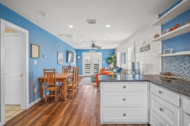 kitchen with ceiling fan, dark stone countertops, dark hardwood / wood-style flooring, white cabinets, and decorative backsplash