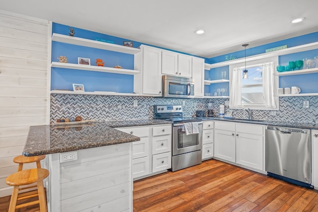 kitchen featuring stainless steel appliances, pendant lighting, sink, white cabinetry, and light hardwood / wood-style flooring