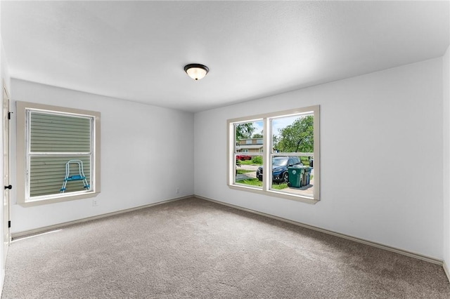 carpeted spare room featuring baseboards
