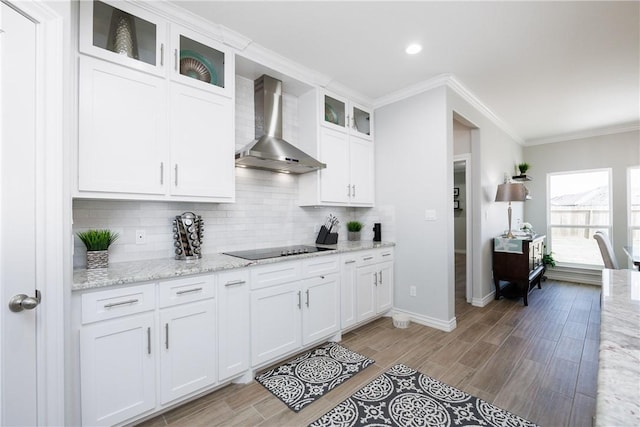 kitchen with ornamental molding, black electric stovetop, wood finish floors, wall chimney range hood, and backsplash