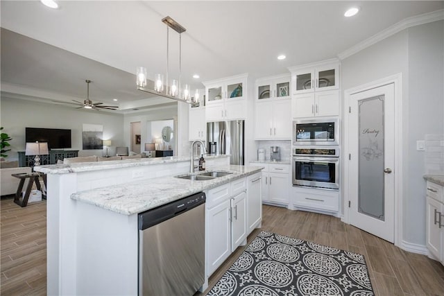 kitchen with a sink, white cabinetry, open floor plan, appliances with stainless steel finishes, and an island with sink