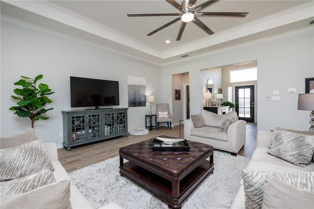 living area featuring visible vents, wood finished floors, a ceiling fan, and crown molding