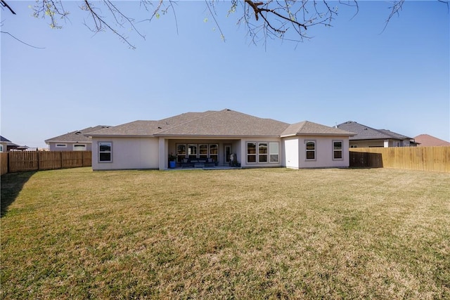 rear view of house featuring a lawn and a fenced backyard