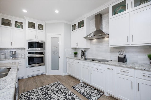 kitchen featuring black electric stovetop, oven, white cabinetry, wall chimney range hood, and built in microwave