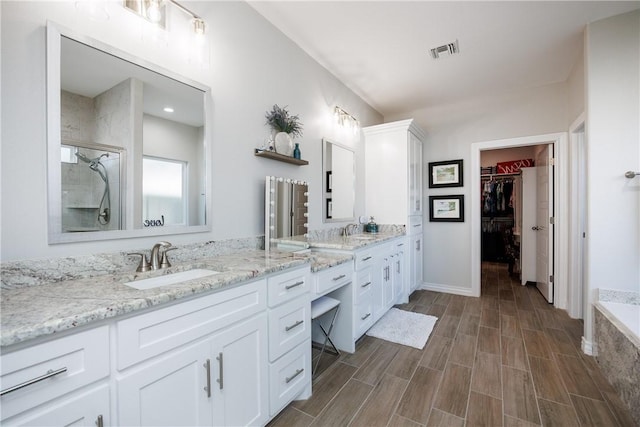 full bathroom featuring double vanity, a stall shower, a sink, and visible vents