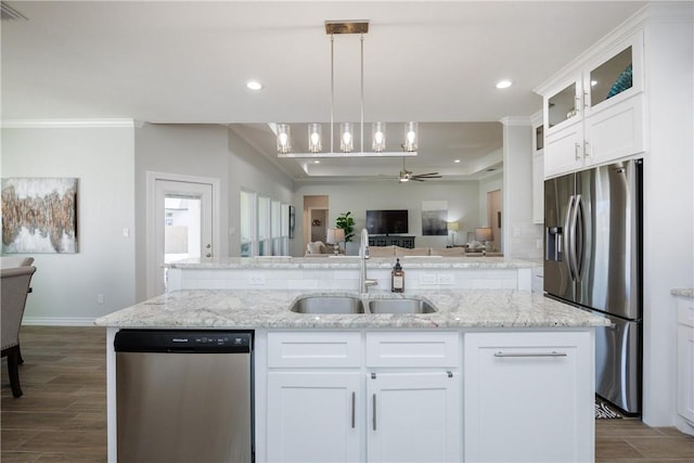 kitchen featuring dark wood finished floors, appliances with stainless steel finishes, open floor plan, a sink, and an island with sink