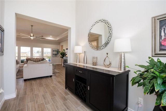 hallway with a tray ceiling, baseboards, and wood tiled floor