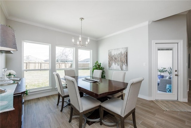 dining room with baseboards, crown molding, light wood finished floors, and an inviting chandelier