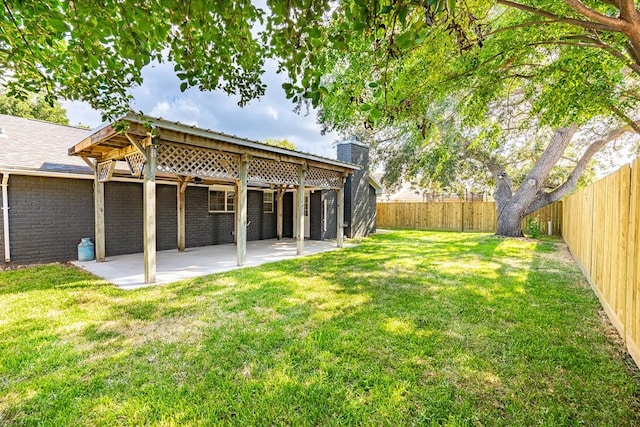 rear view of property featuring a patio, a fenced backyard, brick siding, a yard, and a chimney