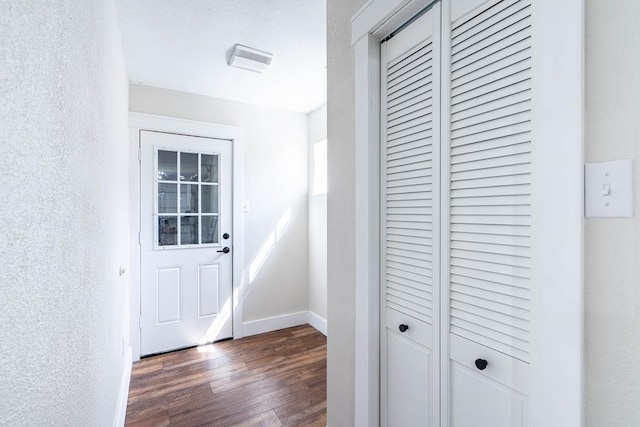 entryway with a textured wall, dark wood finished floors, and baseboards