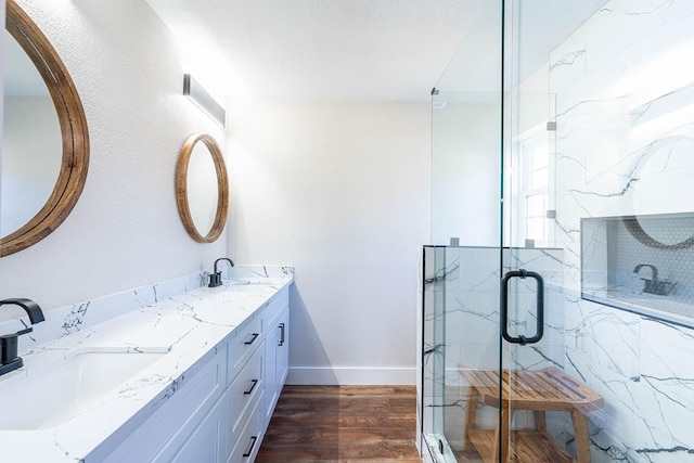 bathroom featuring a marble finish shower, a sink, and wood finished floors