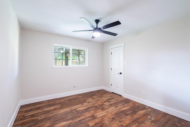 spare room featuring dark wood finished floors, a ceiling fan, and baseboards