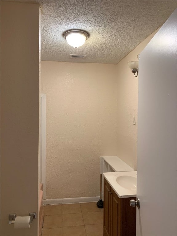 full bath with a textured ceiling, visible vents, baseboards, vanity, and tile patterned floors