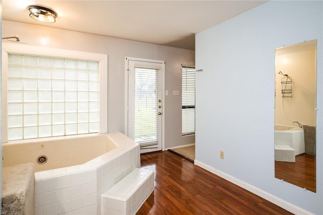 bathroom with tiled bath and wood-type flooring