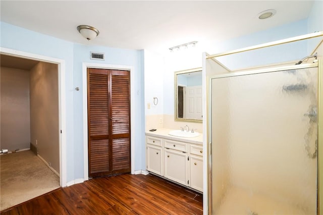 bathroom with walk in shower, vanity, and wood-type flooring